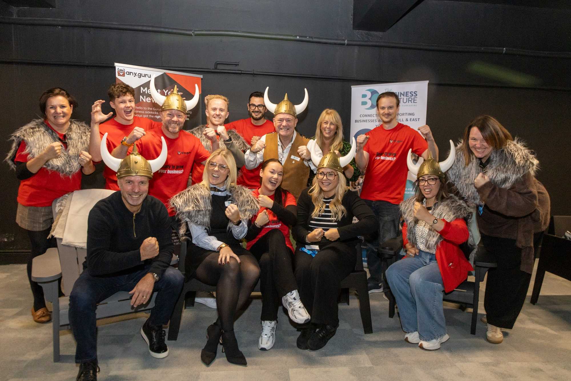 The Any Guru community together at an event, wearing Viking helmets and red Any Guru shirts